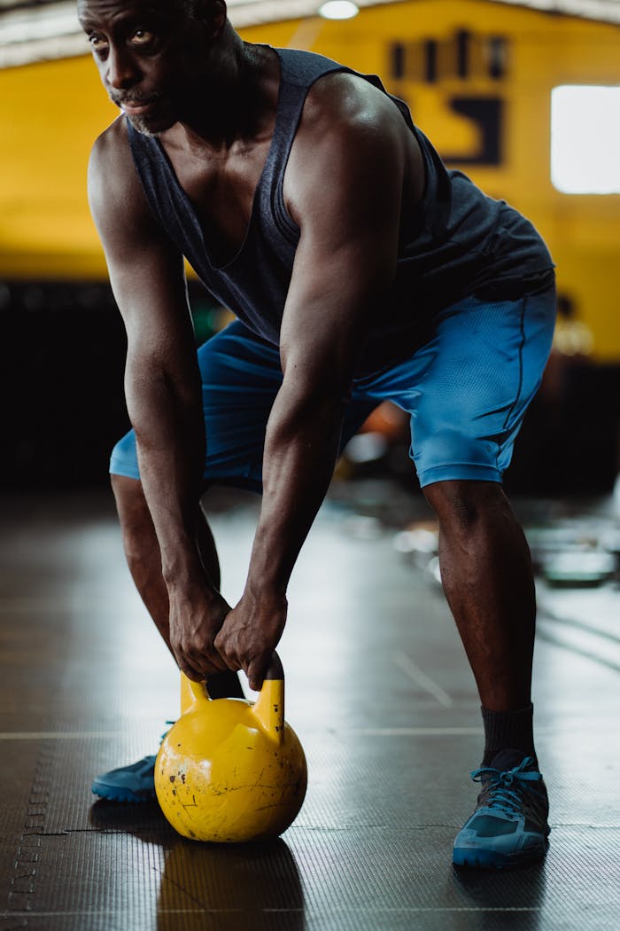 Focused athlete performing kettlebell exercise in a gym setting, showcasing strength and determination.
